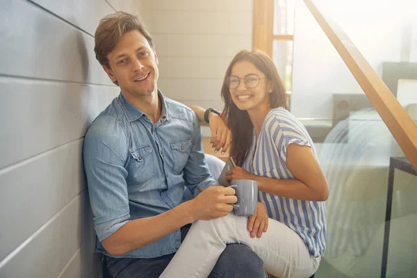 Feliz joven pareja alegre sentado en la habitación moderna — Foto de Stock