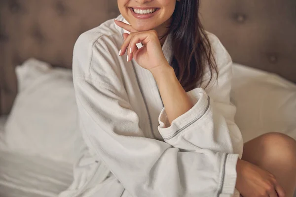 Happy cheerful woman in white bathrobe at home