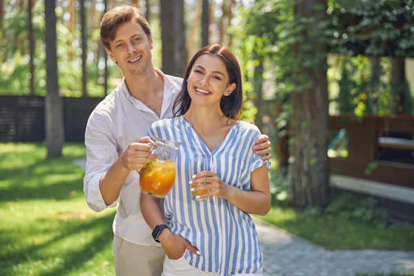 Vackert leende par med apelsinlemonad står i naturen — Stockfoto
