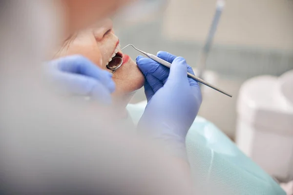 Dentysta badający zęby pacjenta narzędziami stomatologicznymi — Zdjęcie stockowe