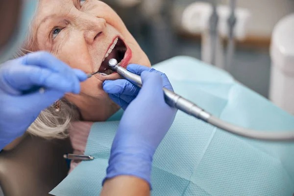 Dentysta robi proces leczenia zębów pięknej starszej białej kobiety — Zdjęcie stockowe