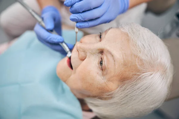 Tandarts behandelen patiënt tanden met tandheelkundig gereedschap in tandheelkundige kliniek — Stockfoto