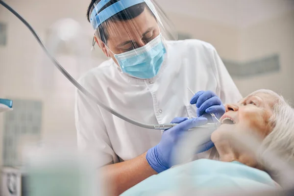 Dojrzały dentysta pracujący ze swoim starszym pacjentem — Zdjęcie stockowe