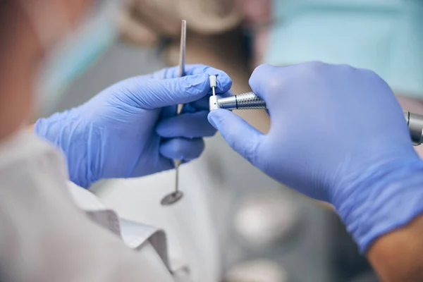 Medico in guanti blu in possesso di attrezzature dentista in mano — Foto Stock