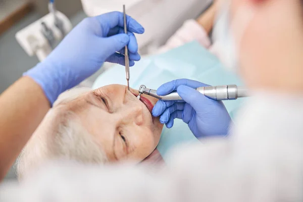 Professionele tandarts werkt met patiënt in kliniek — Stockfoto