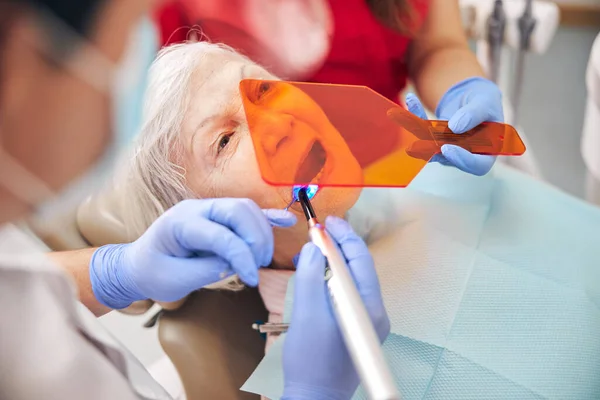 Dentysta używa ultrafioletowego narzędzia do utwardzania światła — Zdjęcie stockowe