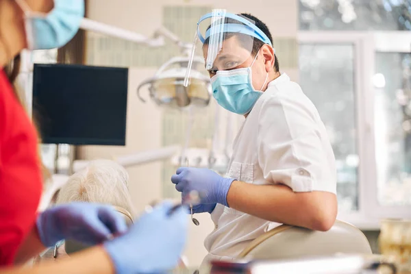 Homme en uniforme de protection assis sur la chaise du dentiste — Photo