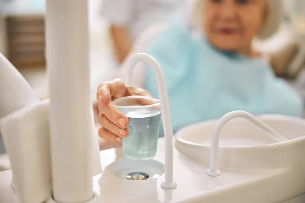 Elderly woman holding plastic cup with water — Stock Photo, Image