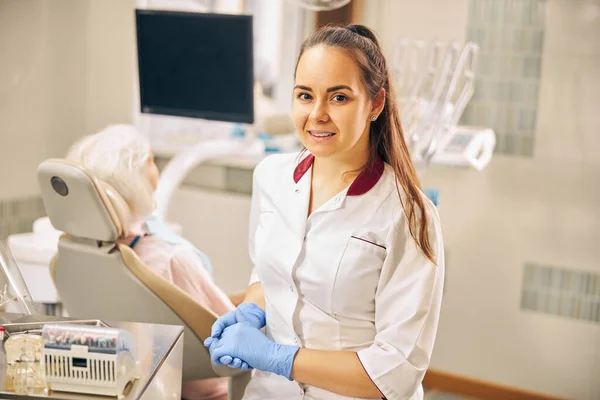Okouzlující evropský zubař v modrých rukavicích sedí na klinice — Stock fotografie