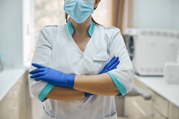 Vrouw met blauwe handschoenen en beschermend masker in tandartskast — Stockfoto