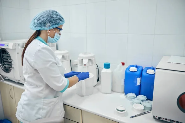 Vrouw in witte badjas werkt met medicijnbereiding in tandheelkundige kliniek — Stockfoto