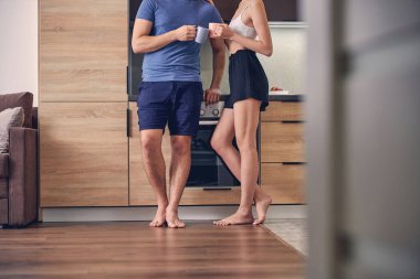 Bir çift mutfakta yaz kıyafetleriyle vakit geçiriyor.