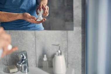 Mavi tişörtlü adam tıraş olmaya hazırlanıyor.