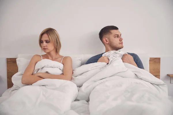 Unga attraktiva par som bor i sängen ser ledsen — Stockfoto