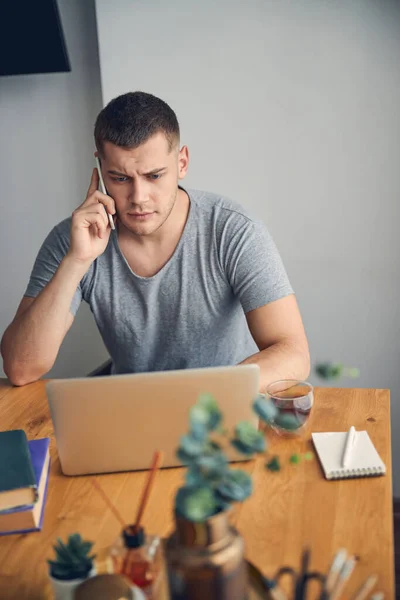 Jeune homme parlant au téléphone tout en étant assis — Photo