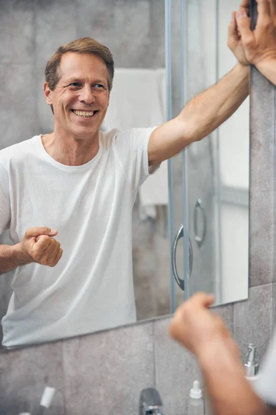 Een man die zijn blik in de spiegel bewondert — Stockfoto