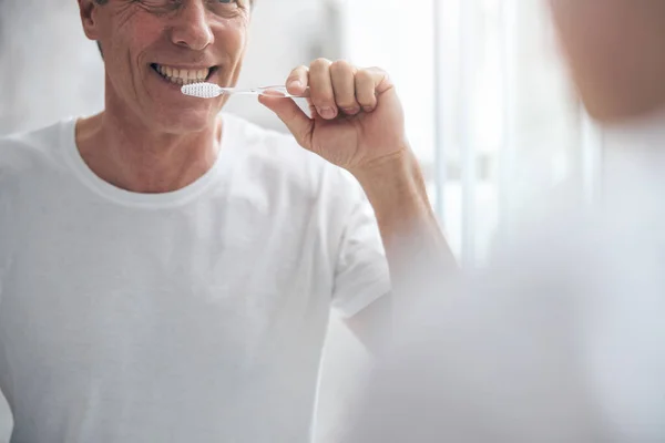 Joyous middle-aged male maintaining his oral hygiene — Stock Photo, Image