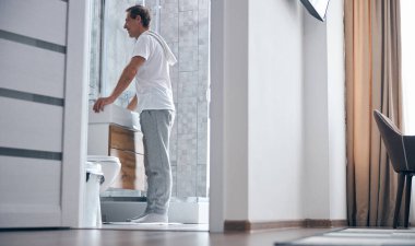 Yakışıklı adam aynada kendine bakıyor.