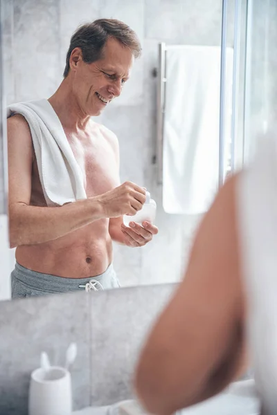 Hombre alegre mirando el aftershave en sus manos — Foto de Stock