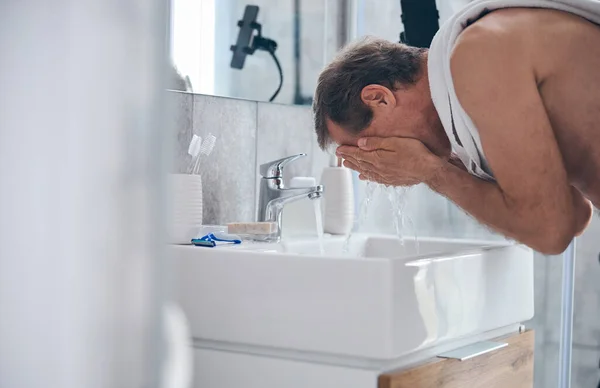 Korthårig man tvättar ansiktet med vatten — Stockfoto