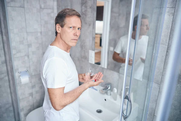 Mężczyzna z kapsułek witaminy stojących w łazience — Zdjęcie stockowe
