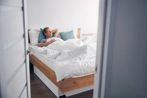 Snäll äldre man liggande i sin mysiga säng — Stockfoto