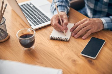 İnternetteki toplantıda not almakla meşgul bir ofis çalışanı.