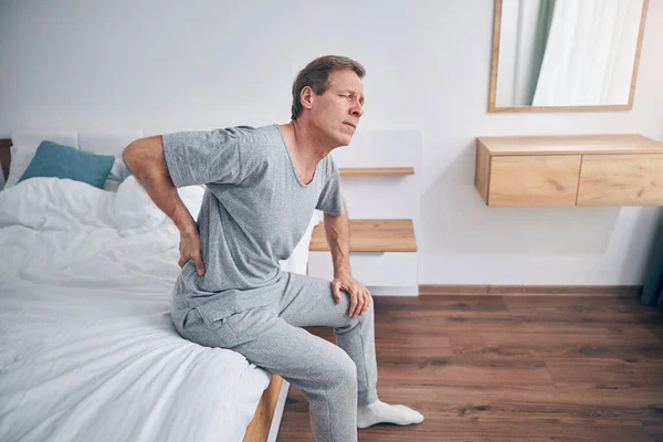 Mature male person having sharp pain in back — Stock Photo, Image