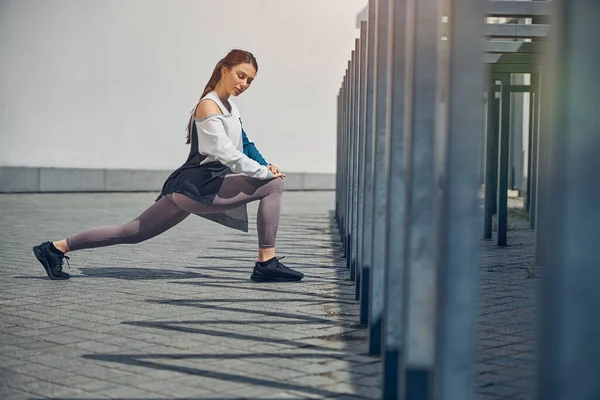 Serena esportista em leggings esticando as pernas — Fotografia de Stock