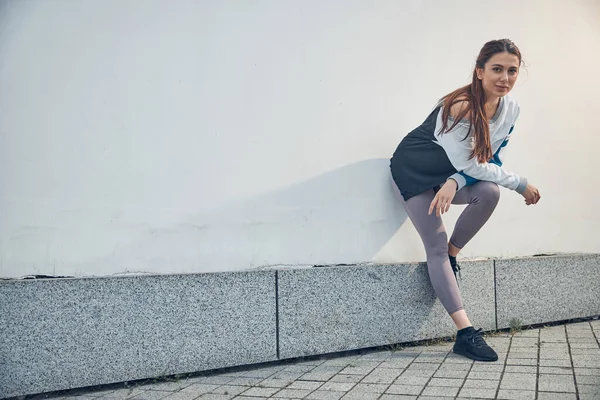 Sporty dai capelli lunghi femmina in piedi vicino a un muro — Foto Stock