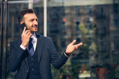 Genç beyaz erkek dışarıda akıllı telefondan konuşuyor.