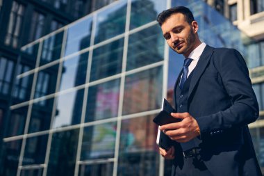 Çekici esmer iş adamı cep telefonuna bakıyor.