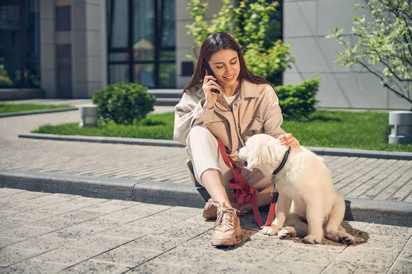 Γυναίκα με ένα smartphone κοιτάζοντας το κατοικίδιο ζώο της — Φωτογραφία Αρχείου