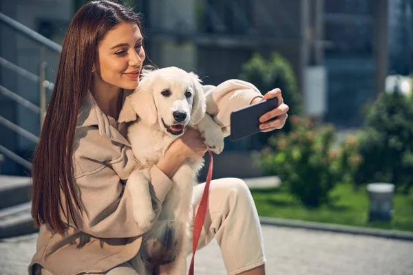 Dame souriante se photographiant avec son chien à l'extérieur — Photo