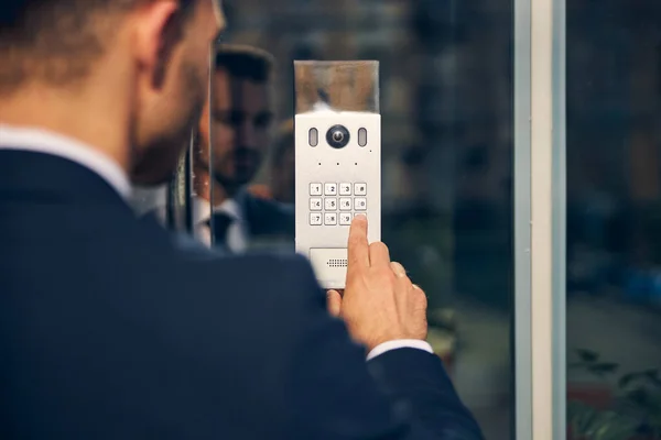 Young man trying to enter building touching buttons — Stock Photo, Image