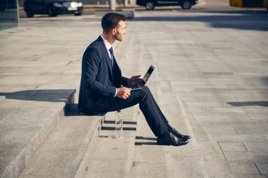 Genç esmer adam dışarıda aletle bekliyor.