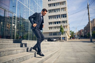 Yakışıklı esmer adam baharda merdivenlerden iniyor.