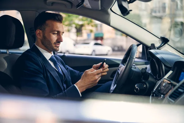 Attraente bruna maschio che rimane in auto con il telefono — Foto Stock