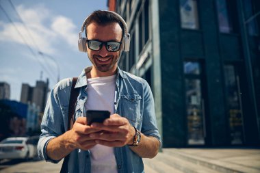 Neşeli genç adam telefonda gelir mesajı okuyor.