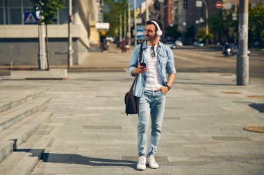 Sokakta yürüyen keyifli genç bir erkek.