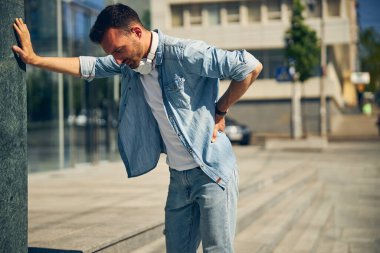 Binanın yanında duran üzgün genç adam.