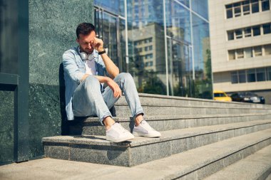 Genç esmer üzgün merdivenlerde oturuyor.