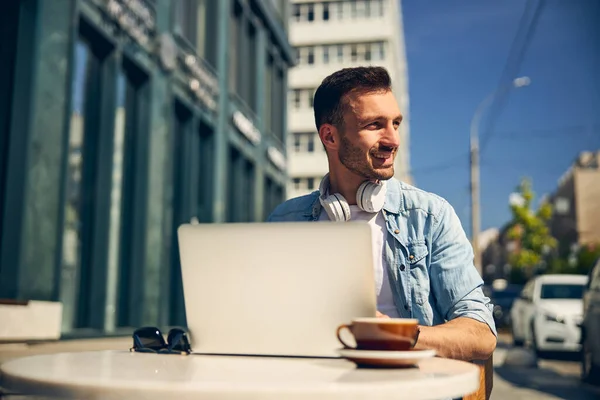 Positiv beglückter Freiberufler sitzt vor seinem Laptop — Stockfoto