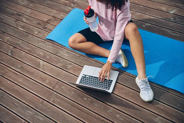 Wanita sporty menghabiskan waktu dengan komputer pada tikar yoga — Stok Foto
