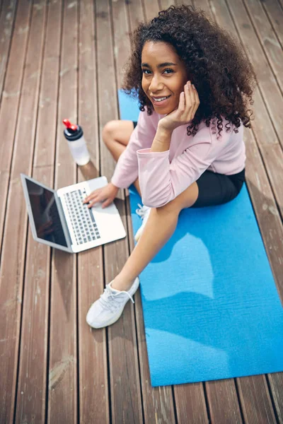 Mulher bonito com cabelo encaracolado relaxante com seu computador — Fotografia de Stock