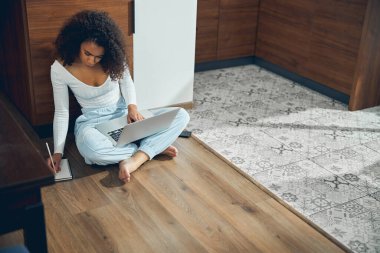 Çıplak ayaklı serbest çalışan yere notlar alıyor.