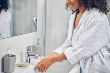 Banyo musluğunun altında kaplamalı kadın avuçları var.