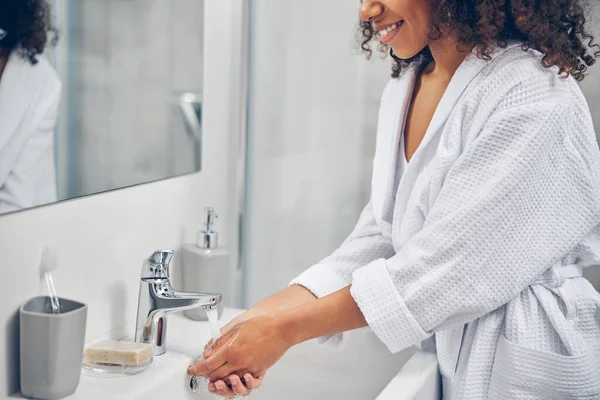 Banyo musluğunun altında kaplamalı kadın avuçları var.