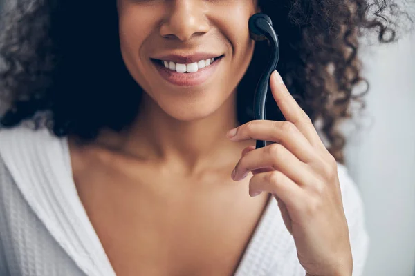 Contentada mulher de cabelos escuros fazendo uma massagem facial — Fotografia de Stock