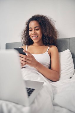 Gülümseyen genç bayan cep telefonunu kullanıyor.